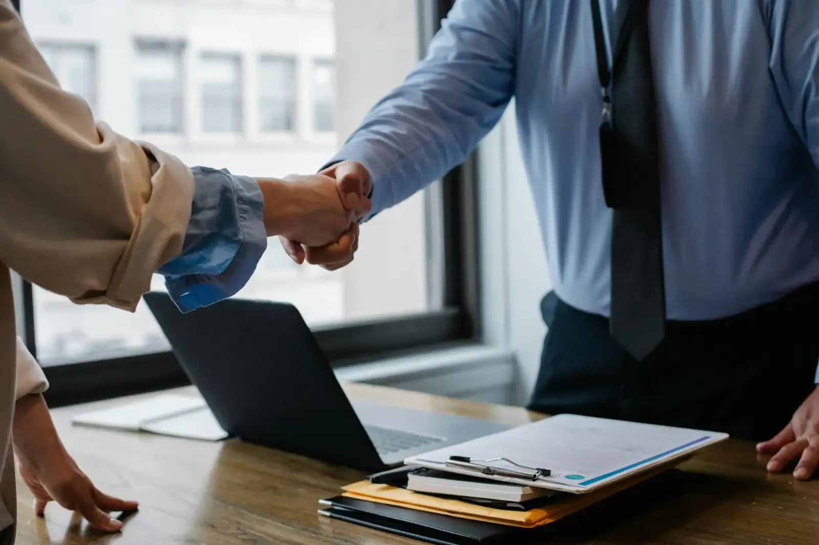 Two business partners shaking hands across a desk